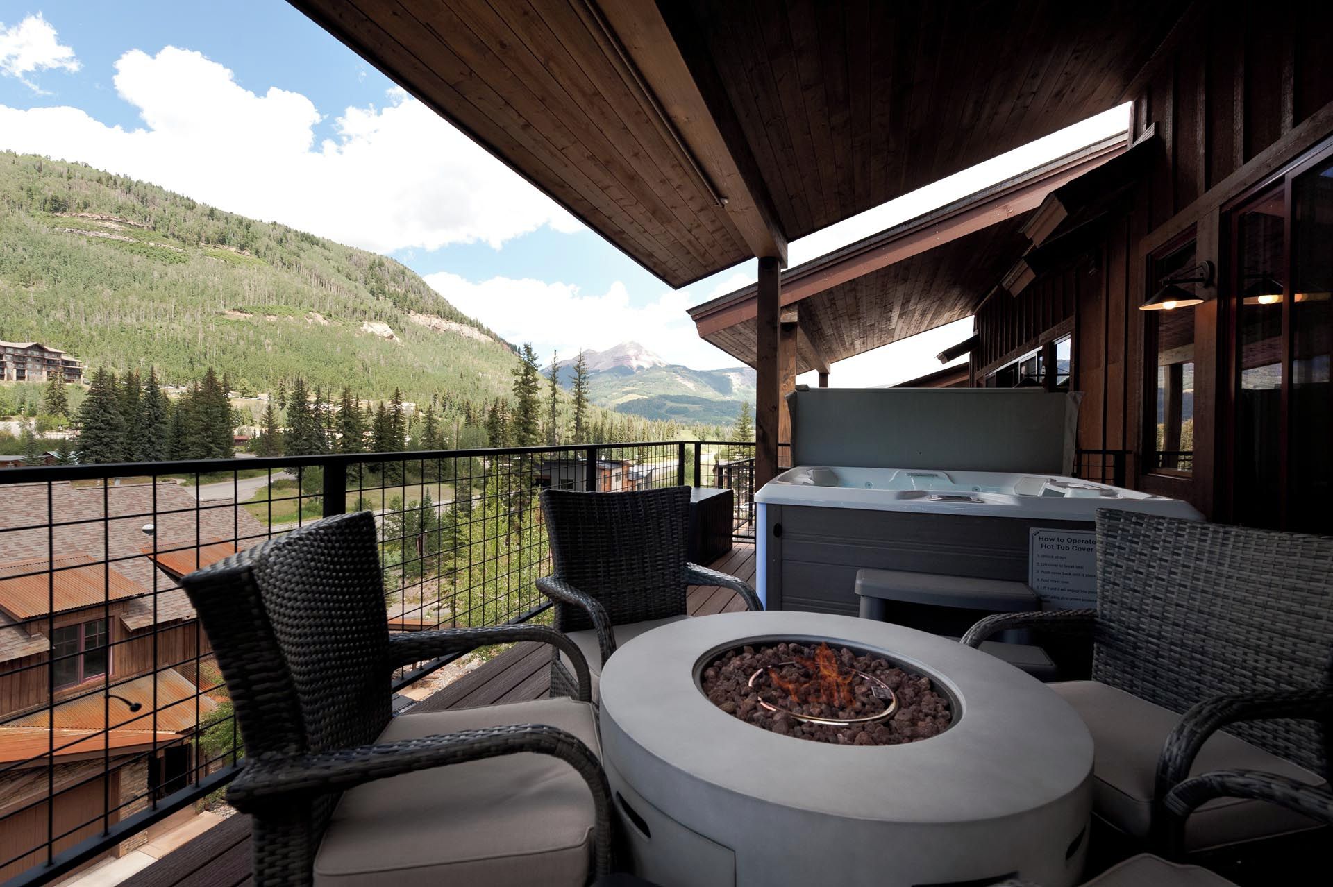 A balcony with wicker furniture, a fire pit, and a hot tub.