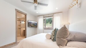 A bedroom with a bed, a television, a window with curtains, and a ceiling fan. - Brand New Townhome Across from Purg - Hot Tub/Arcade Game/Views/EV Charger (Durango)