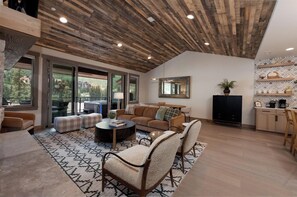A spacious living area with a high ceiling, a large window, and a cozy seating arrangement. - Brand New Townhome Across from Purg - Hot Tub/Arcade Game/Views/EV Charger/AC (Durango)