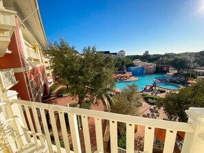 A hotel balcony overlooking a pool area with a water slide and a view of the surrounding landscape. - Orlando | Disney Leisure Escape | Pool + Walkable BoardWalk (Lake Buena Vista)