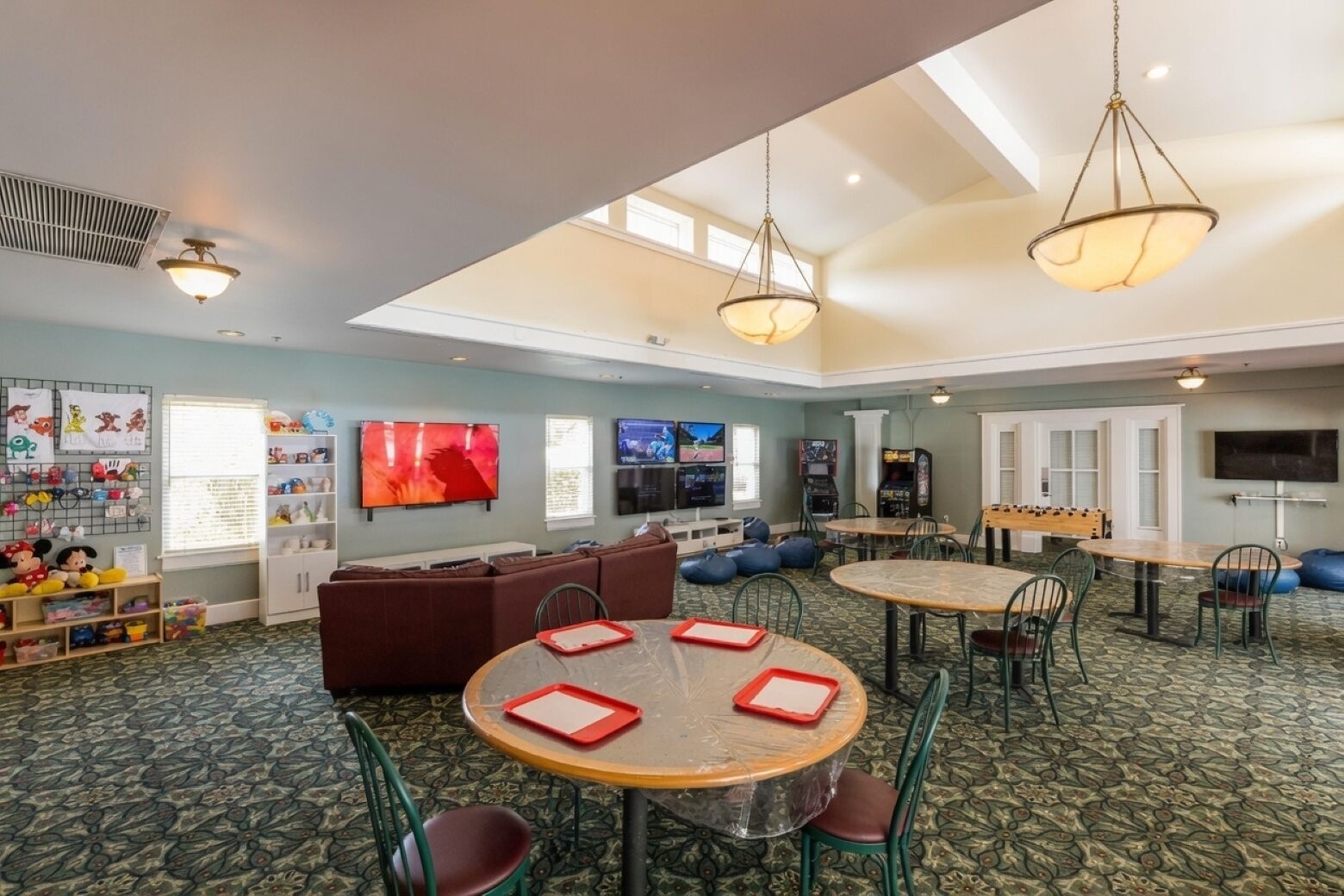 A children's play area with seating, tables, and entertainment options like TVs and arcade games.