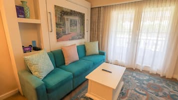 Un soggiorno con un divano color acquamarina, un tavolino da caffè bianco e un quadro raffigurante un giardino.