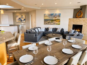 Ein modernes Wohnzimmer mit einem Ecksofa, einem Esstisch für sechs Personen und einem Kamin.
