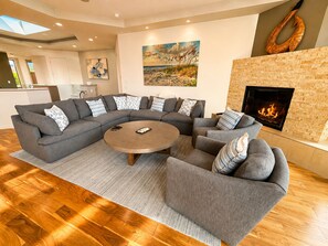 A modern living room with a sectional sofa, a round coffee table, and a fireplace. - Bodega Bay~5BR~Hot Tub~Game Room~Golf~Near Doran Beach~Coastal View~Sleeps 12 (Bodega Bay)