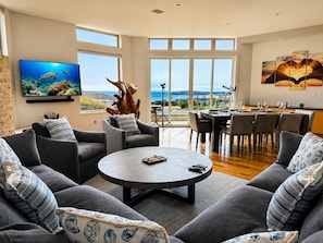 A spacious living room with a large window, a dining area, and a view of the ocean. - Bodega Bay~5BR~Hot Tub~Game Room~Golf~Near Doran Beach~Coastal View~Sleeps 12 (Bodega Bay)