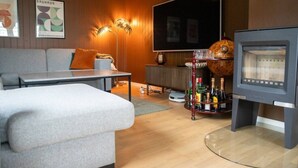 A modern living room with a sofa, a coffee table, a flat-screen TV, a fireplace, and a globe. - Spacious Aurora Family Home (Tromsø)