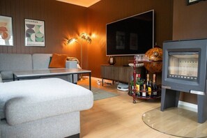 Ein modernes Wohnzimmer mit Sofa, Couchtisch, Flachbildfernseher, Kamin und Globus.
