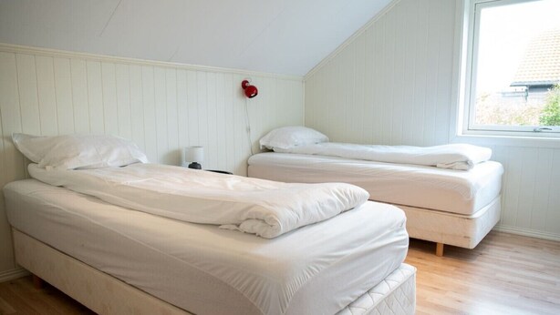 A room with two beds, a window, and a wall-mounted red object. - Spacious Aurora Family Home (Tromsø)