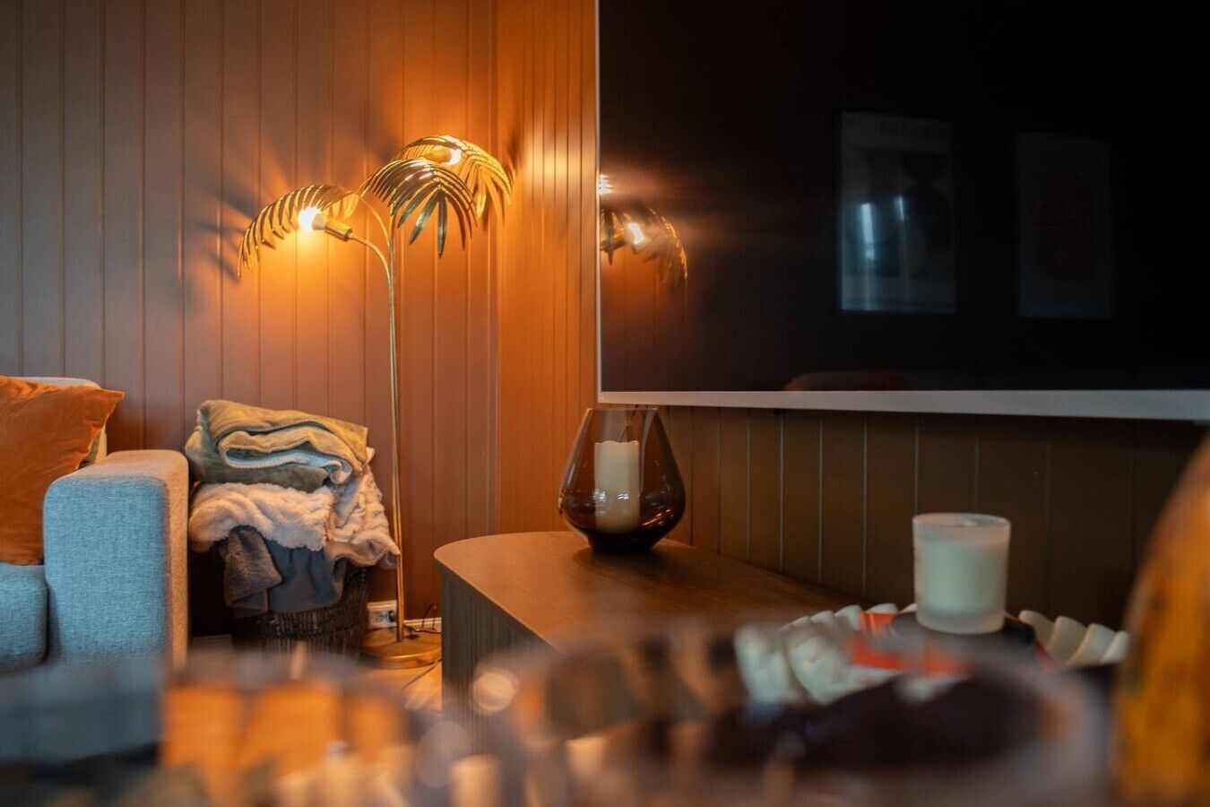 A cozy living area with a sofa, a floor lamp, and a table with candles.