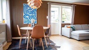 A modern living room with a round dining table, leather chairs, a grey sofa, and a large abstract painting on the wall. - Spacious Aurora Family Home (Tromsø)