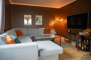 Ein modernes Wohnzimmer mit einem Ecksofa, einem Couchtisch, einem Flachbildfernseher und einer Bar mit Flaschen.