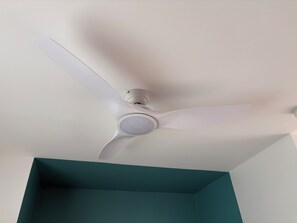 A ceiling fan with three blades and a central light fixture in a room with teal walls. - CLAPOTIS, 100 m from the beach (Saint-Pierre)