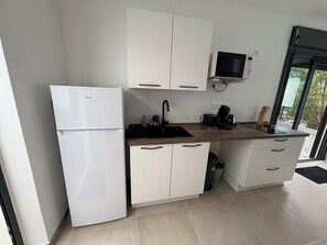A modern kitchen with white cabinets, a built-in microwave, a refrigerator, a sink, and a coffee maker. - CLAPOTIS, 100 m from the beach (Saint-Pierre)