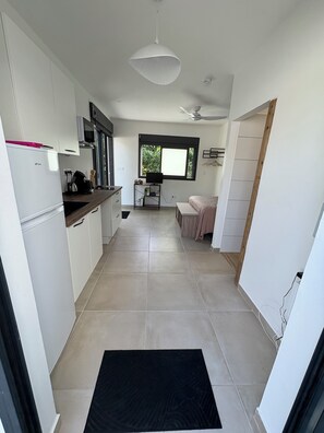 A modern kitchen with white cabinets, a black countertop, and a window with a view of greenery. - CLAPOTIS, 100 m from the beach (Saint-Pierre)