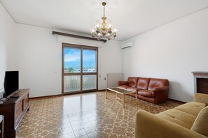 Una sala de estar con sofá, televisor, mesa de centro y candelabro.