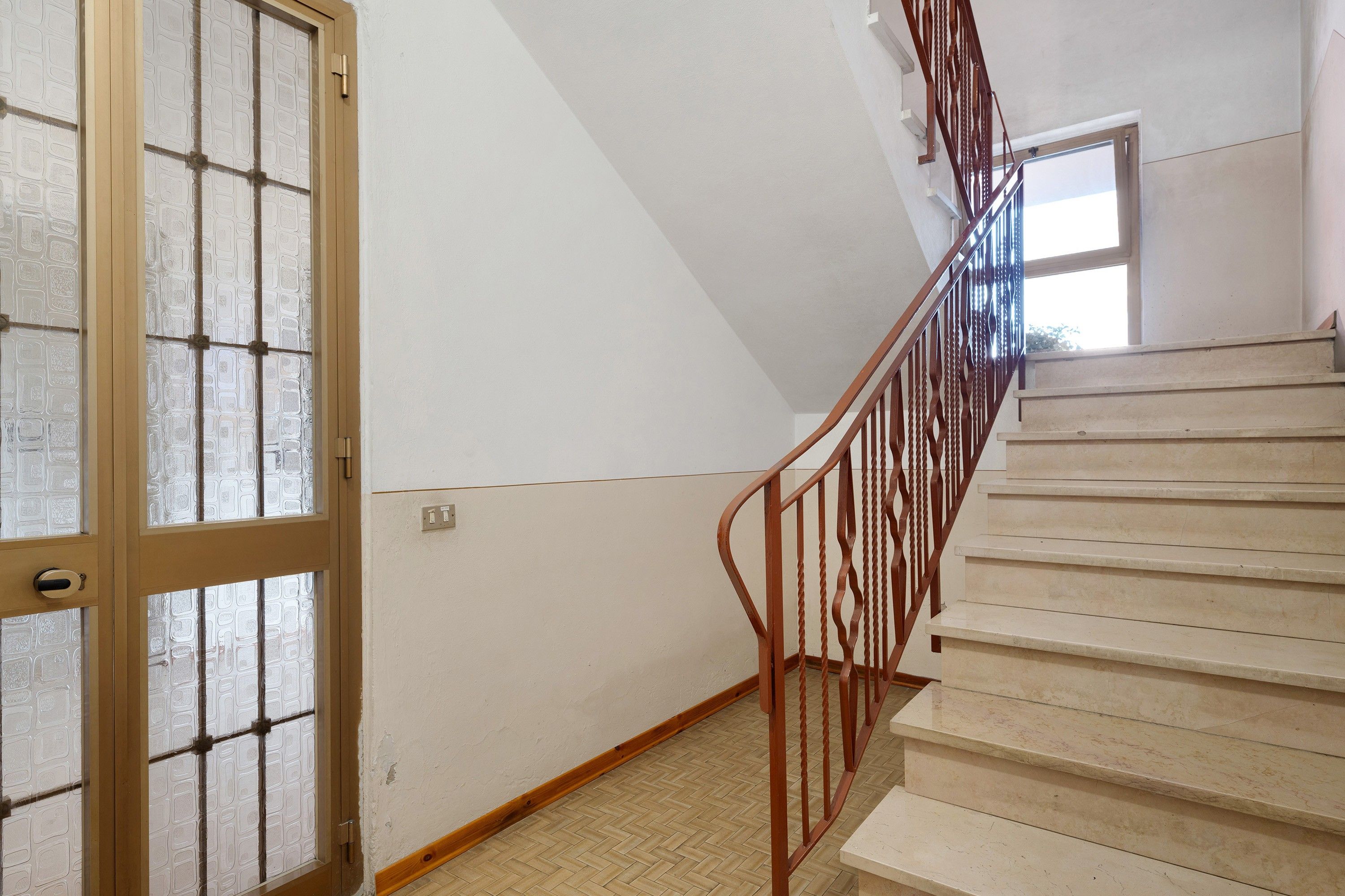 Eine Treppe mit Holzwertlauf und gefliestem Boden.