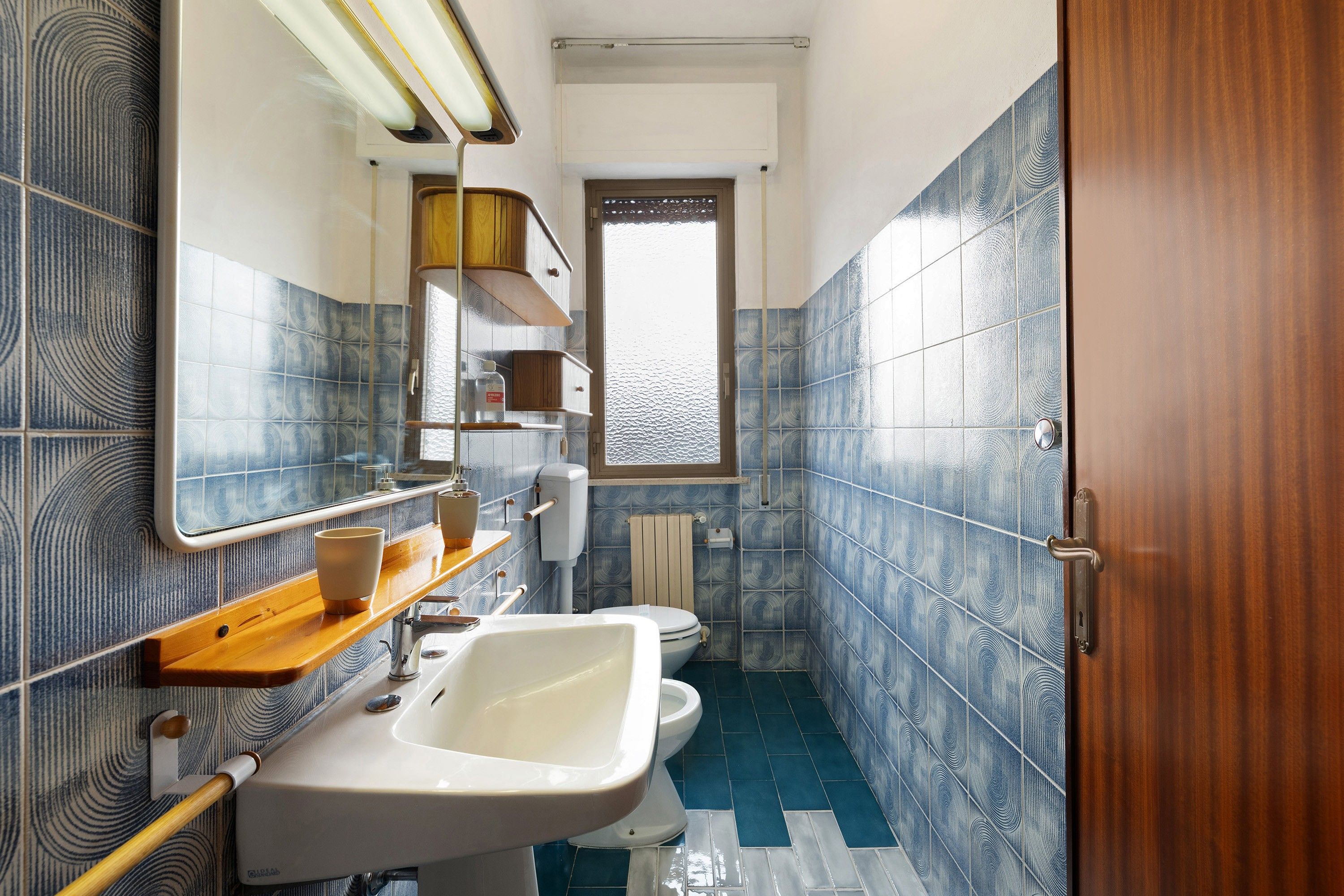 A bathroom with a sink, toilet, and a window.
