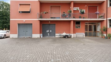 Ein mehrstöckiges Gebäude mit roter Fassade, Balkonen mit Blumentöpfen und einem gepflasterten Innenhof.