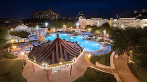A nighttime view of a resort with a swimming pool, a carousel, and a building labeled 'Family Amusement.' - Orlando | Relaxed Group Resort Stay | Pool + Walkable BoardWalk | 2BR Lock-Off (Lake Buena Vista)