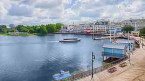 A waterfront area with a dock, a boat, and a building with a blue awning. - Orlando | Relaxed Group Resort Stay | Pool + Walkable BoardWalk | 2BR Lock-Off (Lake Buena Vista)