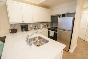 A kitchen with white cabinets, a stainless steel sink, a built-in oven, and a refrigerator. - Orlando | Relaxed Group Resort Stay | Pool + Walkable BoardWalk | 2BR Lock-Off (Lake Buena Vista)
