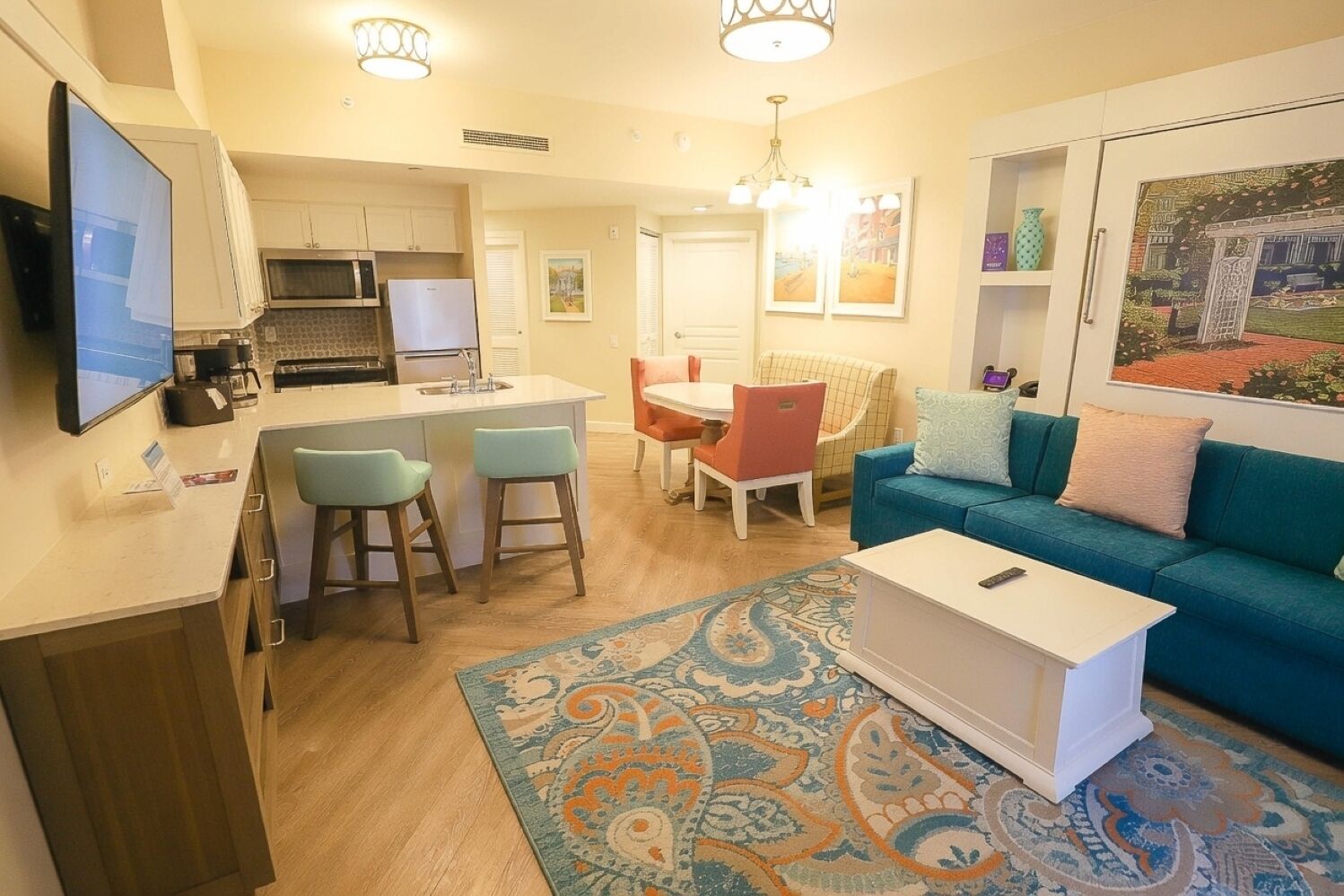 A compact living space with a kitchenette, a dining area, and a seating area with a sofa and chairs.