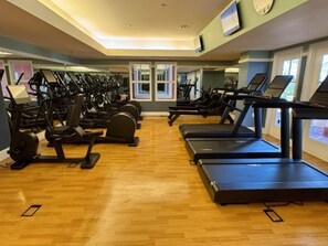 Una palestra con diverse tapis roulant ed ellittiche disposte in file.