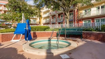 Un área de piscina con un jacuzzi circular, un tobogán azul y un banco verde.