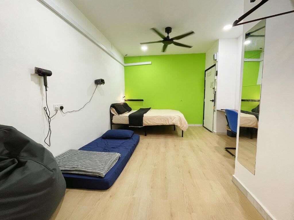 A compact room with a bed, a small desk, a chair, and a ceiling fan.