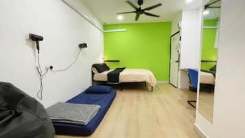Una habitación compacta con una cama, un escritorio pequeño, una silla y un ventilador de techo.