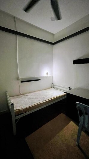 A small, single-bed room with a desk and chair, a ceiling fan, and a wall-mounted shelf. - D Cloud Homestay & Room (Kajang)