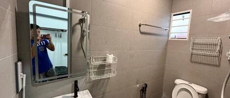 A bathroom with a sink, toilet, mirror, and towel racks.