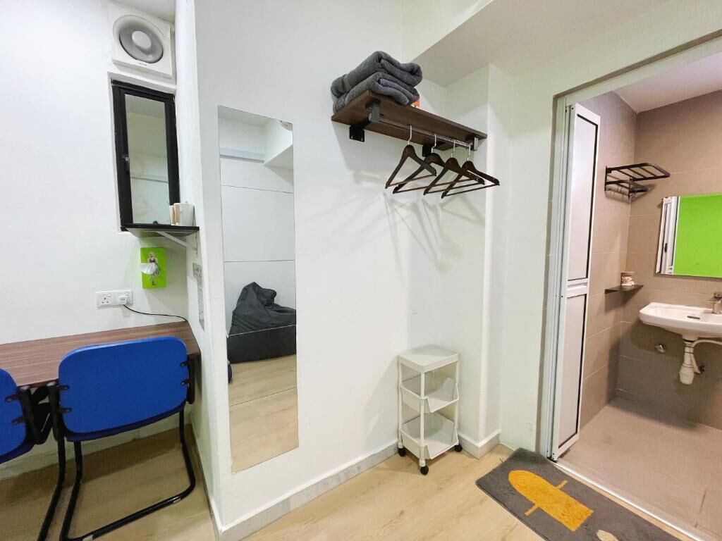 A compact room with a desk, chair, mirror, and a small white shelf.