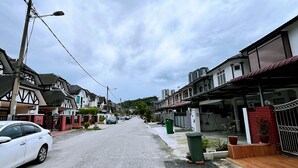 A residential street with houses, a parked white car, and a street lamp.