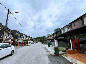 Una calle residencial con casas, un auto blanco estacionado y una farola.