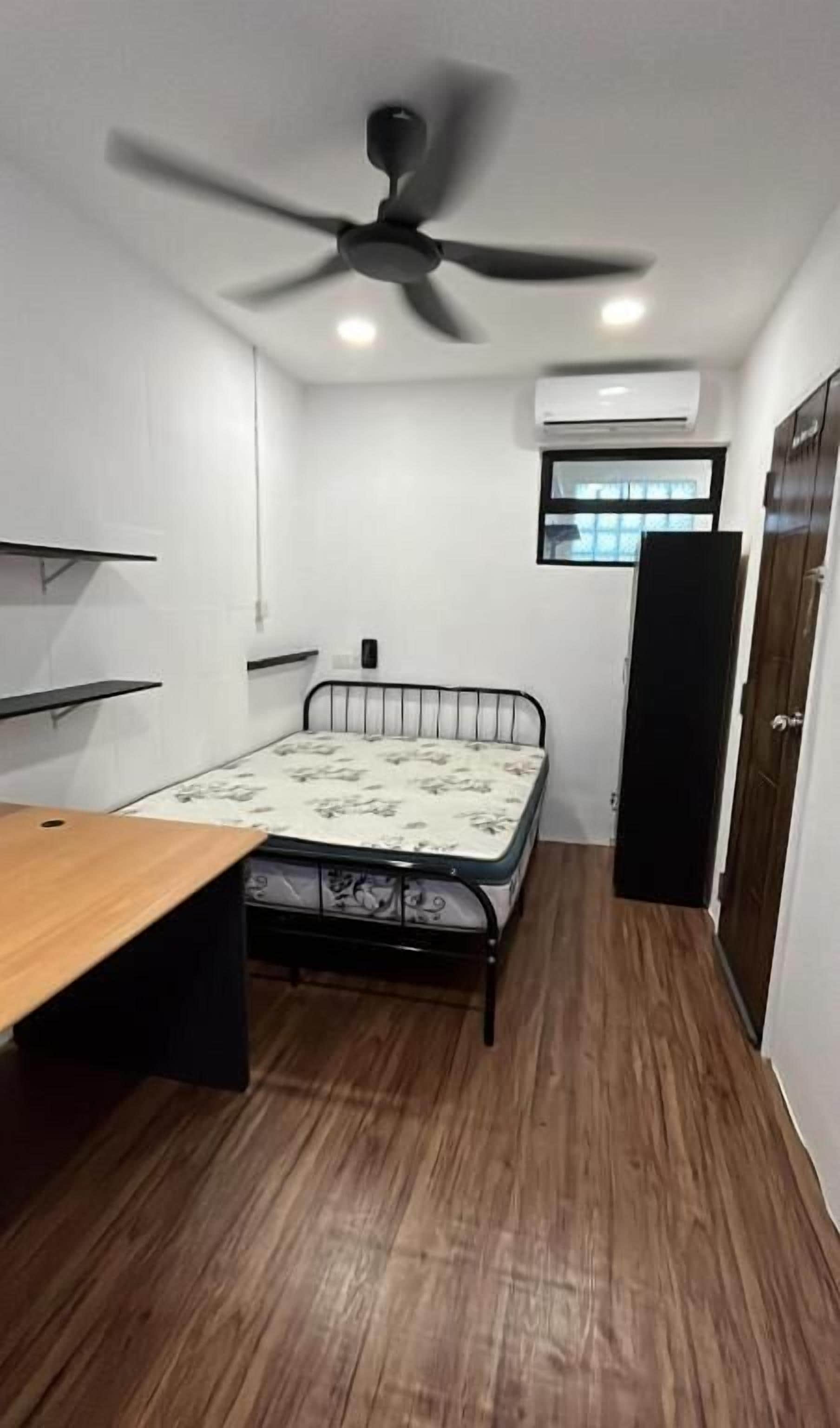 A room with a bed, a desk, a ceiling fan, and an air conditioning unit.