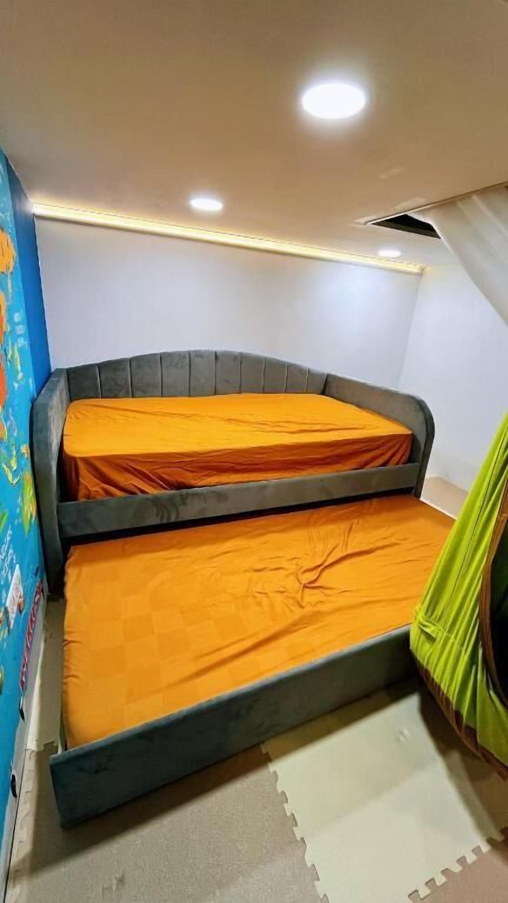 A bunk bed with two levels, a ceiling with recessed lighting, and a wall with a colorful mural.