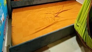 Uma cama beliche com dois níveis, teto com iluminação embutida e parede com um mural colorido.