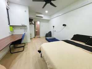 A compact hotel room with a bed, a desk, and a ceiling fan.