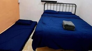 Quarto com duas camas, uma com colcha azul e a outra com colcha cinza.