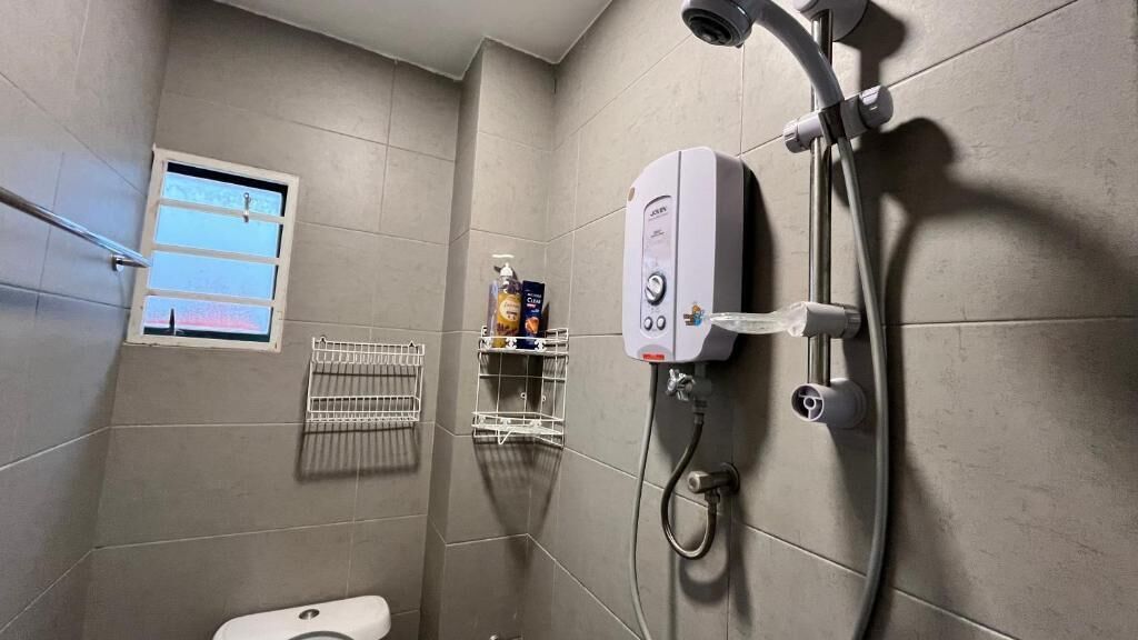 A modern bathroom with a shower, toilet, and a window.