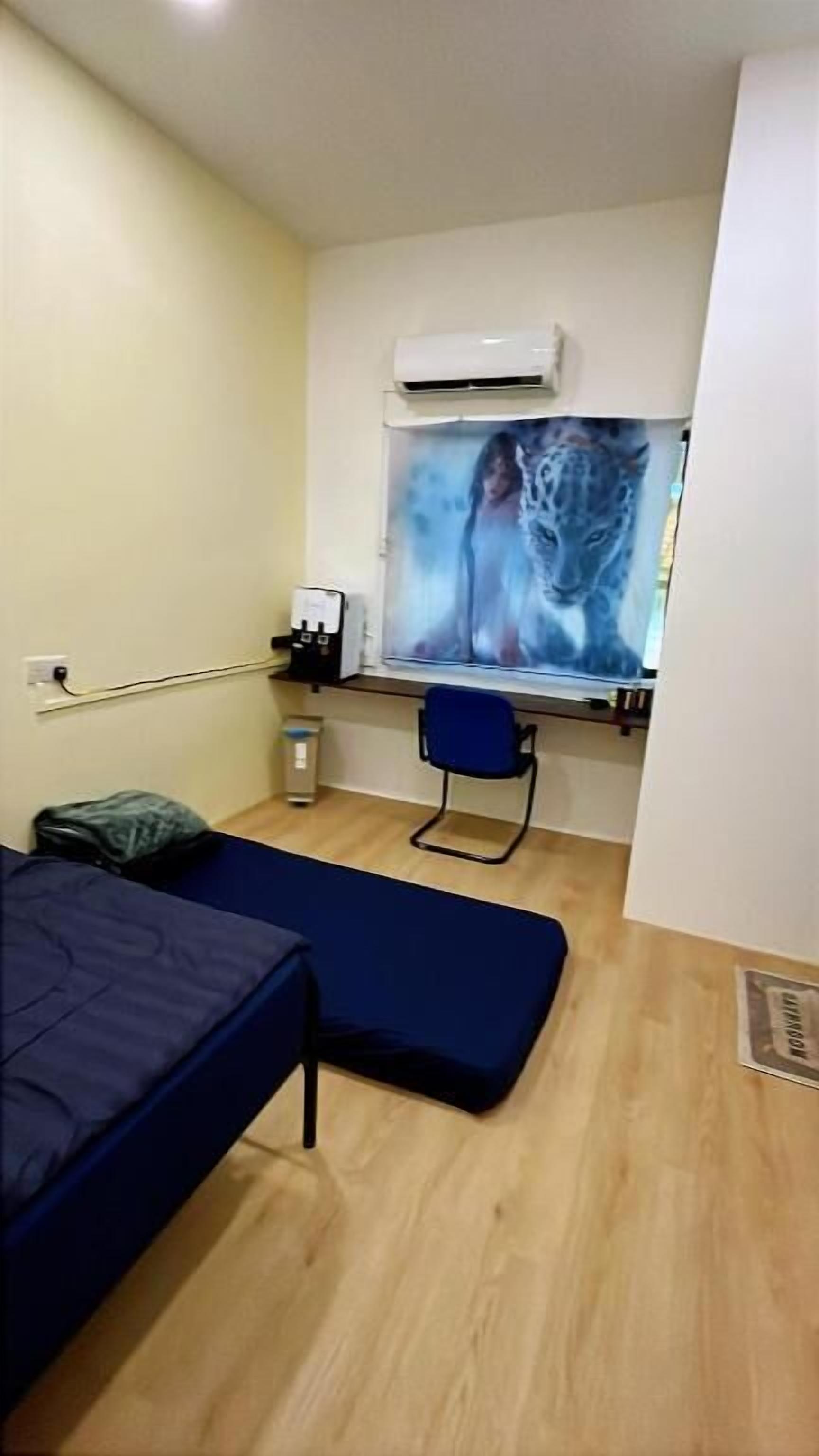 Una habitación pequeña con una cama, una silla, un escritorio con una computadora y una ventana con estampado de leopardo.