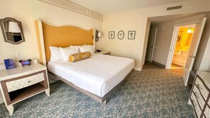 A hotel room with a bed, bedside table, lamp, and artwork on the wall. - Orlando | BoardWalk Family Gathering | Pool + Walkable | 3BR Sleeps 12 (Lake Buena Vista)