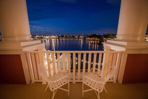 A balcony with two white chairs and a view of a body of water at dusk. - Orlando | BoardWalk Family Gathering | Pool + Walkable | 3BR Sleeps 12 (Lake Buena Vista)