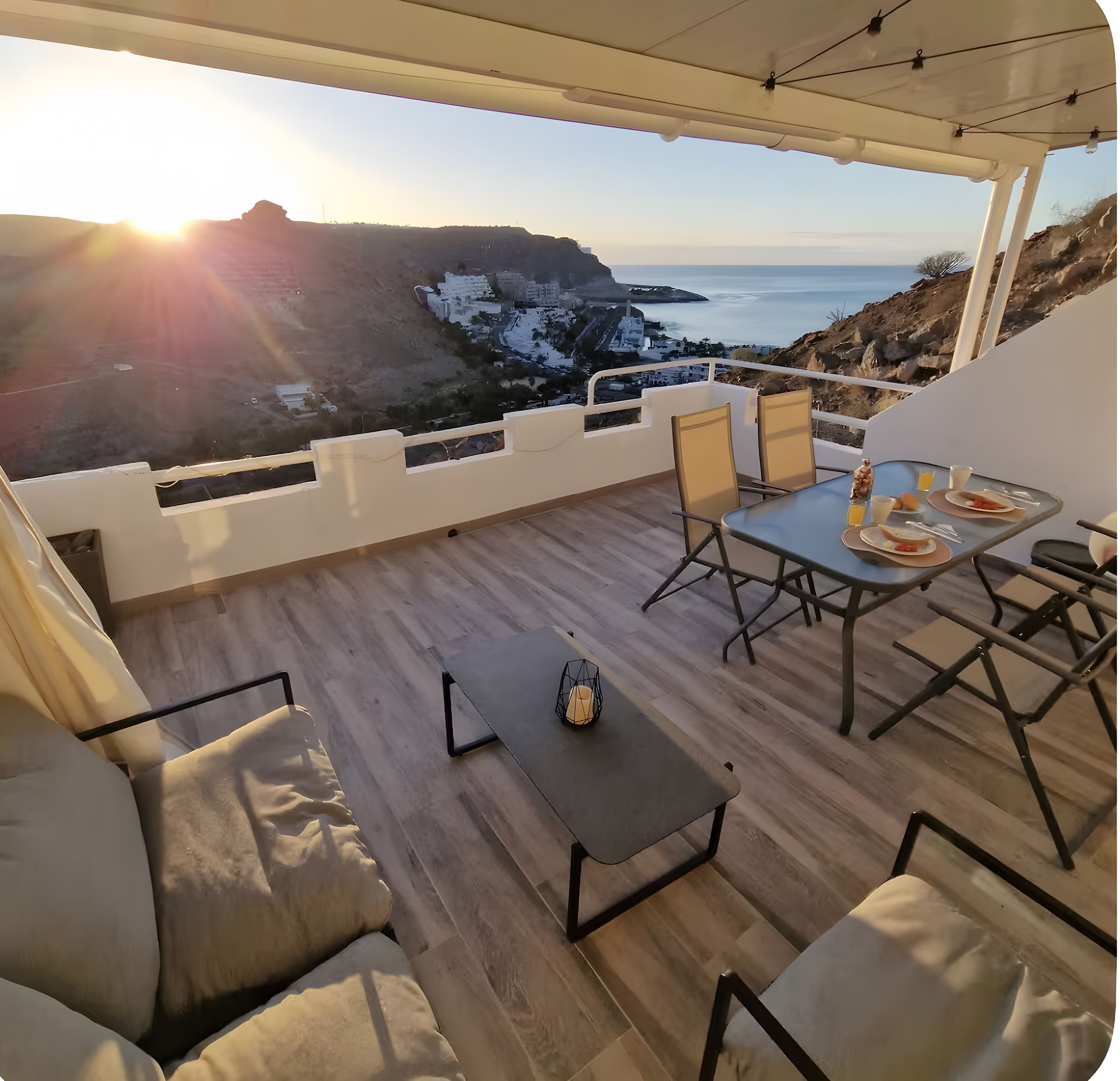 Eine Terrasse mit gedecktem Tisch für das Frühstück, mit Blick auf eine Küstenlandschaft.