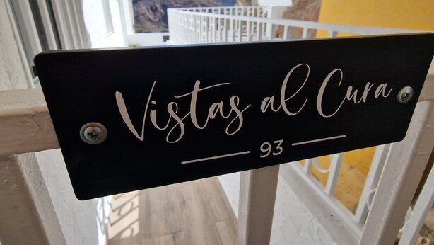 Een bord met de tekst 'Vistas al Cura' en het nummer '93' op een zwarte achtergrond.