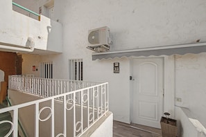 A white exterior with a metal railing, a door, and a sign indicating room number 93.