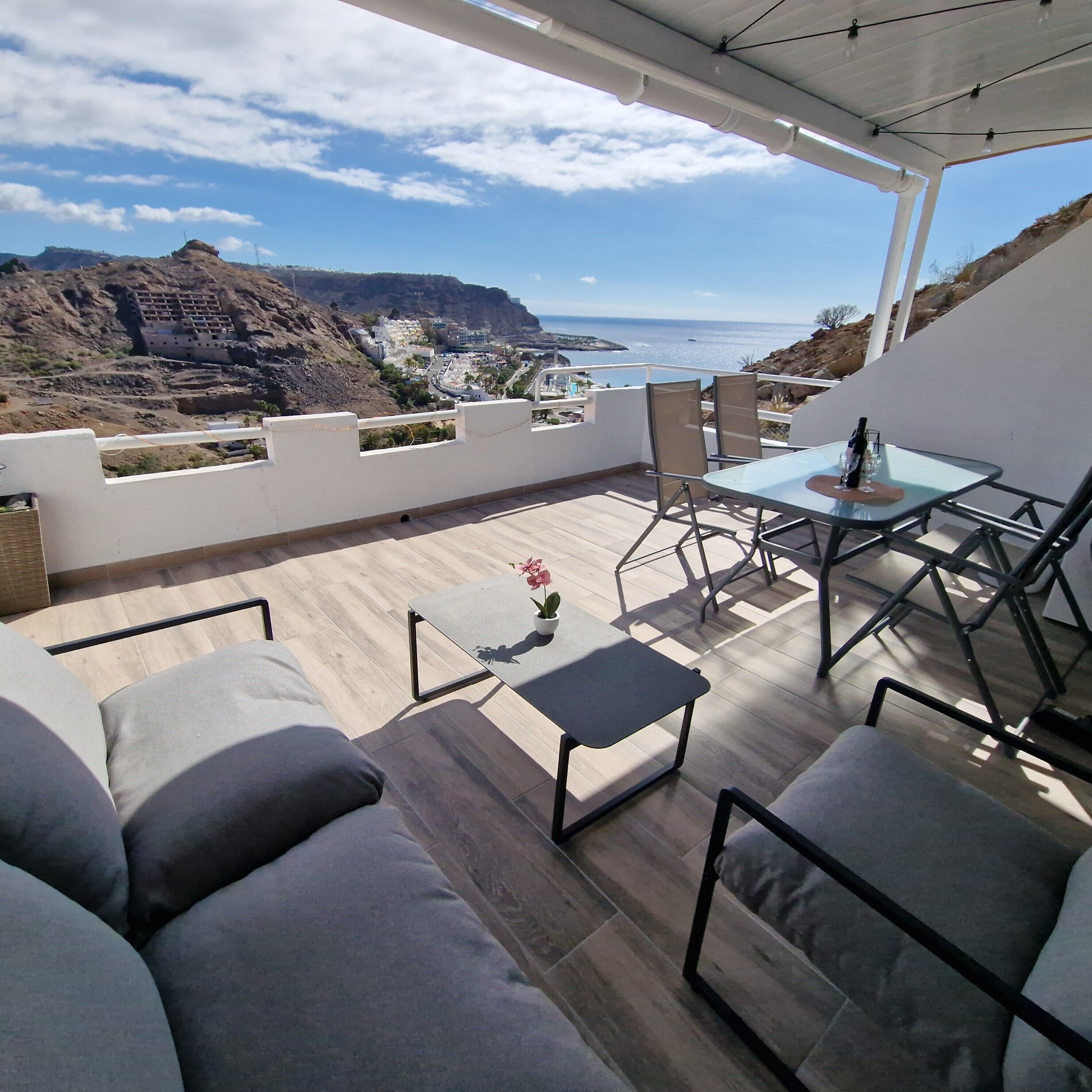 Una terraza con vistas al mar, amueblada con un sofá, sillas y una mesa.
