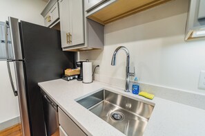 Eine Küche mit Spüle aus Edelstahl, einer Kaffeemaschine und einem Kühlschrank.