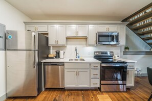 A modern kitchen with stainless steel appliances, white cabinetry, and a wooden floor. - Designer Loft - Parking Nearby Hospitals - 2F (Louisville)